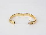 a gold cuff bracelet with a black diamond in the middle