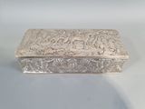 une boîte argentée posée sur une surface blanche et ornée d'un motif
