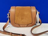 un sac à bandoulière en cuir marron posé sur une table blanche