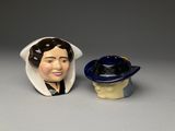 two ceramic figurines of a woman and a hat on a table