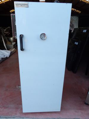 un réfrigérateur blanc posé dans un garage, avec d'autres appareils électroménagers en arrière-plan