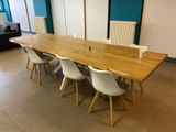 a long wooden table with white chairs in a room