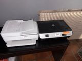two printers sitting on a table next to a radiator