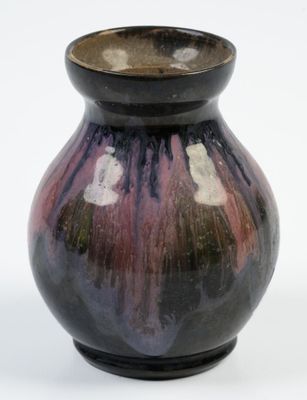 un vase noir et violet posé sur une surface blanche