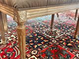 un banc sur lequel est posé un coussin, posé à son tour sur un tapis