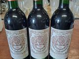 trois bouteilles de vin posées sur une table en bois, à côté d'une étiquette de prix