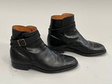 paire de bottines en cuir noir ornées de boucles sur un fond blanc