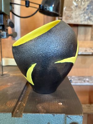 un bol noir et jaune posé sur un morceau de bois