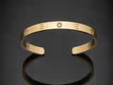 a gold cuff bracelet with a diamond in the middle