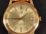 a gold watch with a brown leather strap on a black surface