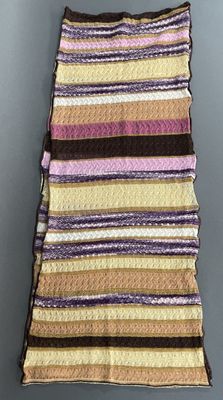 a multicolored striped blanket hanging on a wall