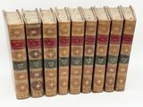 six old books are lined up in a row on a white surface
