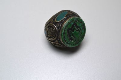 Gros plan sur une bague ornée d'une pierre verte