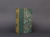 an old book with a green cover sitting on top of a table