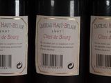 three bottles of red wine are lined up on a shelf