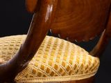 a close up of a wooden chair with a yellow upholstered seat