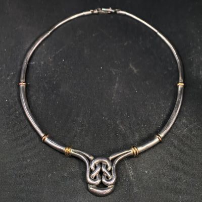 un collier en argent orné d'un nœud celtique sur un fond noir