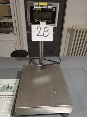 une balance numérique posée sur une table recouverte d'un journal