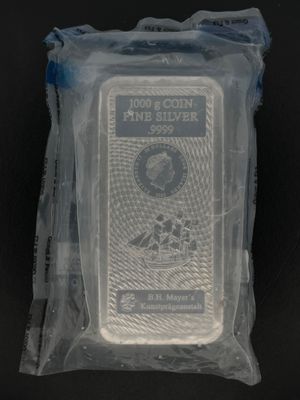 un gros plan d'un lingot d'argent emballé dans du plastique, posé sur une surface noire