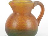 un vase marron et vert muni d'une anse, sur un fond blanc