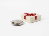 a small white box with a red ribbon and a silver button on it
