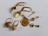 plusieurs paires de boucles d'oreilles en or et une montre en or posées sur une surface blanche