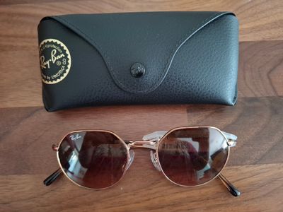 Des lunettes de soleil Ray-Ban et leur étui posés sur une table en bois
