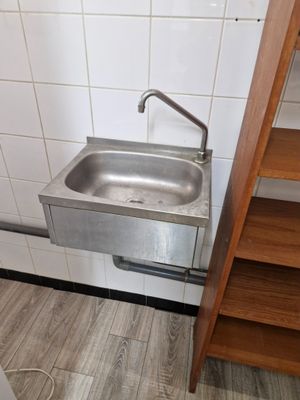 un lavabo dans un coin de la salle de bains, avec une étagère en bois