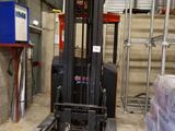 un chariot élévateur dans un entrepôt où il y a beaucoup de cartons par terre