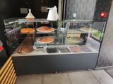 a glass display case filled with pizzas and pastries