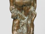 statue of a man sitting on top of a rock with his hands in his pockets