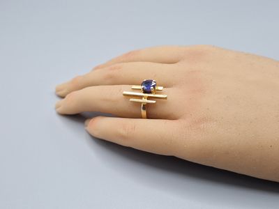a woman ' s hand holding a ring with a blue stone on it