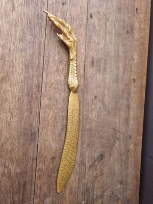 a gold feather shaped object on a wooden table