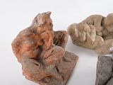three clay sculptures of a man sitting on a rock next to a pile of rocks