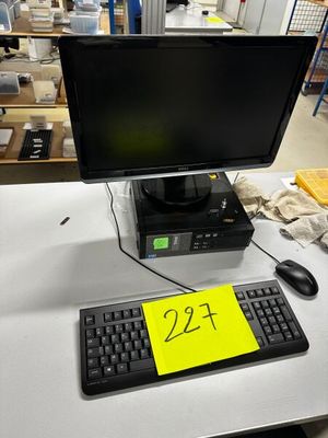un écran d'ordinateur et un clavier posés sur un bureau dans un entrepôt