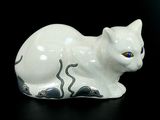 une figurine de chat blanc posée sur une surface noire