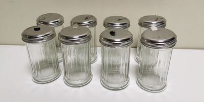 six salières et poivrières en verre alignées sur une table