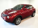the red nissan juke suv is parked in a white room