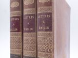 trois livres sont empilés sur une surface blanche