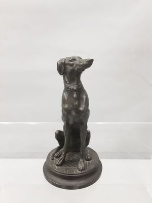a bronze statue of a dog sitting on top of a table