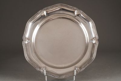 une assiette en argent posée sur un support métallique, sur une table