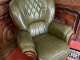 a green leather chair sitting in a corner of a room