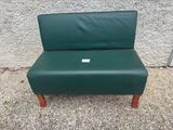 une chaise verte avec une étiquette, posée devant un mur