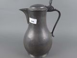 an antique silver pitcher with a bird on the handle