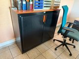 une armoire noire avec une chaise bleue à côté