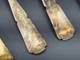 six cuillères et un couteau anciens en argent, posés sur un fond noir