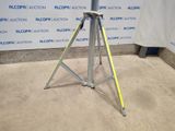 a close up of a tripod on a floor with a sign in the background