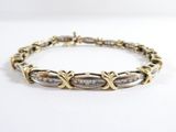 gros plan d'un bracelet en or et en argent sur une surface blanche