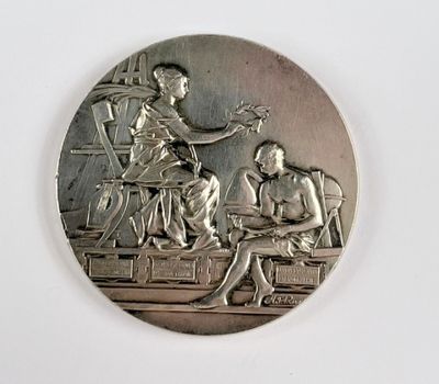 une médaille d'argent représentant un homme et une femme assis à une table