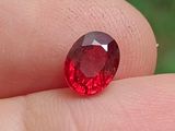 someone is holding a red diamond in their hand on a finger